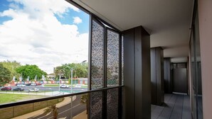 A modern interior with a large window overlooking a street and greenery. - Designer 2BR With Carpark Monash Uni@caulfield (Caulfield North)