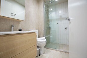 A modern bathroom with a glass shower enclosure, a wooden vanity, and a white toilet. - Designer 2BR With Carpark Monash Uni@caulfield (Caulfield North)