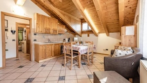 Een gezellige keuken met houten kastjes, een eettafel gedekt voor vier personen en een hoge plafond met zichtbare balken.