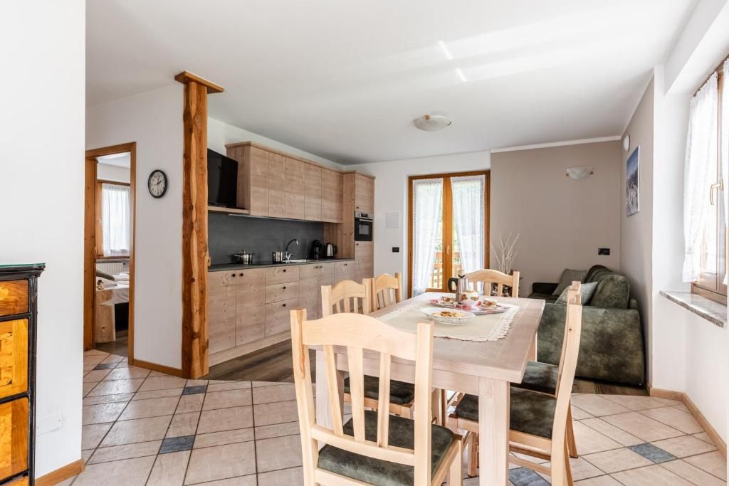 Un'area pranzo con un tavolo e sedie in legno, una cucina sullo sfondo e un divano nell'angolo.