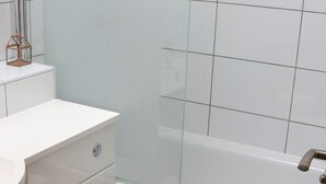 A bathroom with a toilet, a white sink, and a bathtub.