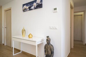A hallway with a white table, two vases, a statue, and a painting on the wall. - Apartamento Rosa Chenz (Mar de Pulpi) (San Juan de los Terreros)