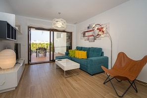 A modern living room with a teal sofa, a white coffee table, and a wooden chair.