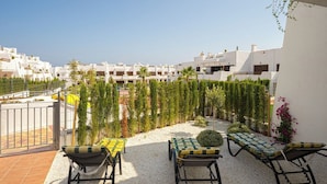 A terrace with outdoor seating, a view of white buildings, and a gravel path. - Apartamento Rosa Chenz (Mar de Pulpi) (San Juan de los Terreros)