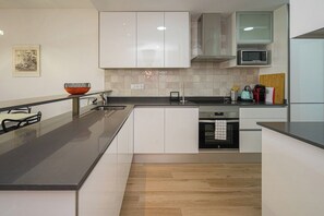 Une cuisine moderne avec des meubles blancs, un plan de travail noir et un four à micro-ondes.