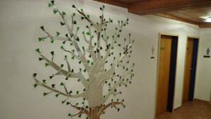 Een gang met een groot muurschildering van een boom, houten deuren en een betegelde vloer.