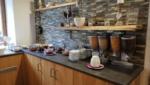 Een ontbijtbuffet met diverse soorten eten, bestek en decoratieve elementen zoals hartjes en kaarsen.