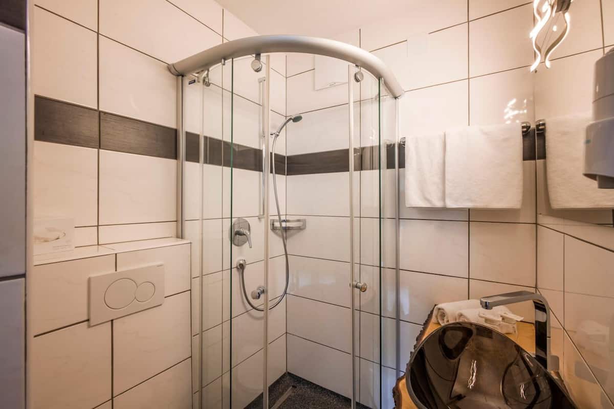 Ein modernes Badezimmer mit einer einteiligen Duschkabine, weißen Fliesenwänden und einem Handtuchhalter.