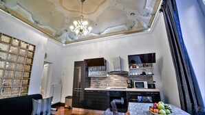 Una cocina moderna con una paleta de colores blanco y negro, una araña y un comedor con una mesa dispuesta para una comida.