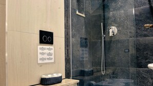 Un baño moderno con ducha de vidrio, dos lavamanos y un inodoro.
