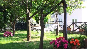 Een tuin met een hangmat, bloemen in potten en een houten hek.