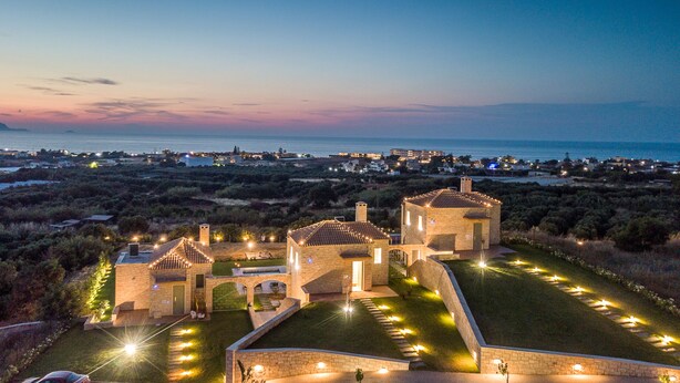 A historic building complex with stone architecture, a well-maintained lawn, and a view of the sea. - Caldera Anissaras Villas (Hersonissos)