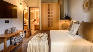 A bedroom with a bed, bedside table, lamp, and a mirror. - Caldera Anissaras Villas (Hersonissos)