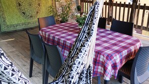Un espace extérieur abrité, aménagé avec une table et des chaises, un luminaire suspendu et un mur décoratif.