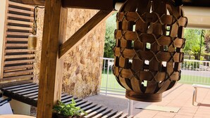 A wooden pergola with a rustic stone wall, a hanging lantern, and a wooden bench with a potted plant.