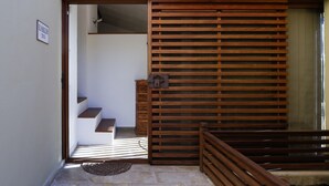 A wooden sliding door with a metal handle, a small wooden bench, and a stone floor leading to a staircase.