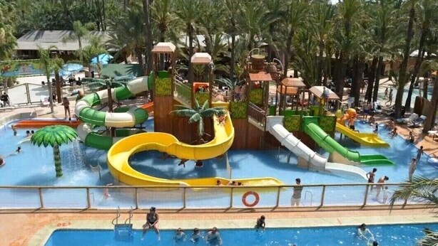 A water park with multiple slides and pools surrounded by palm trees.