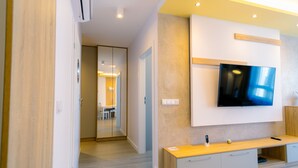Una sala de estar moderna con un televisor de pantalla plana montado en la pared, una consola de madera y un pasillo que conduce a un comedor.