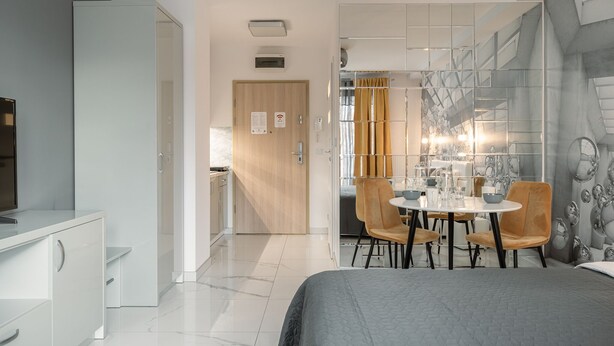 Una habitación de hotel moderna con cama, escritorio, mesa de comedor con sillas y baño con ducha e inodoro.