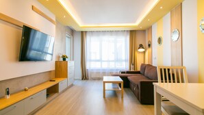 Una sala de estar moderna con televisor de pantalla plana, un sofá, una mesa de centro y un comedor.