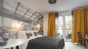 Un dormitorio moderno con una cama grande, una mesa redonda blanca y vistas al exterior a través de un ventanal corredera.