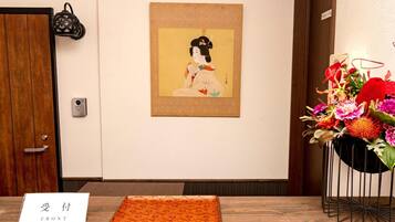 A room with a wooden door, a framed artwork on the wall, a table with a tray, and a vase of flowers.