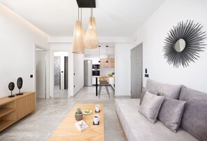Een moderne woonkamer met een grijze bank, een houten salontafel en hanglampen.