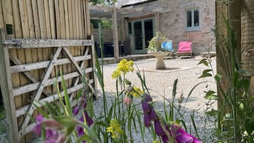 Guests may stroll along the gravel path to the stone building, surrounded by lush plants and flowers.