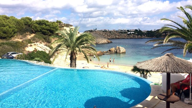 Une piscine avec vue sur une plage et une côte rocheuse.