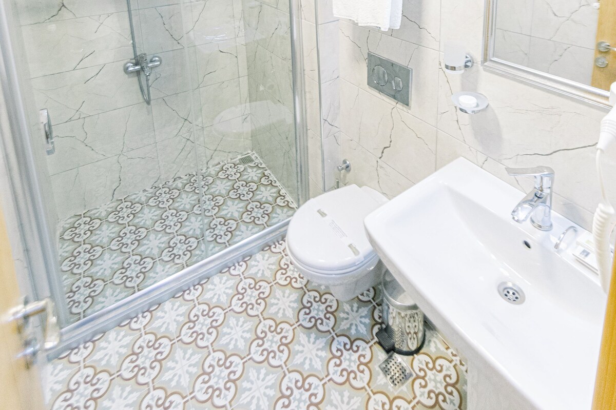 A bathroom with a glass-enclosed shower, a toilet, and a sink.