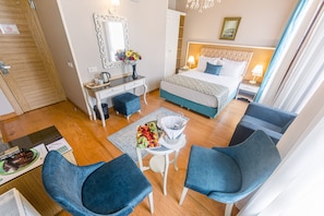 A hotel room with a bed, a desk, two chairs, a dresser, and a mirror. - Acacia Mansion Hotel (Istanbul)