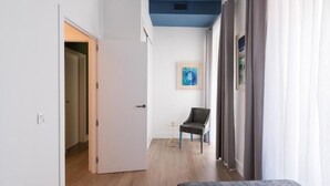 A hallway with a door leading to a room, a small round table with a chair, and a framed picture on the wall. - Tourist apartment, located in the center of Seville (SEVILLA)