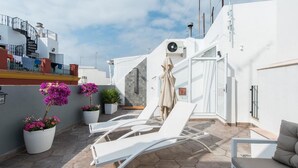 A rooftop terrace with white lounge chairs, a beige towel, and potted plants. - Tourist apartment, located in the center of Seville (SEVILLA)