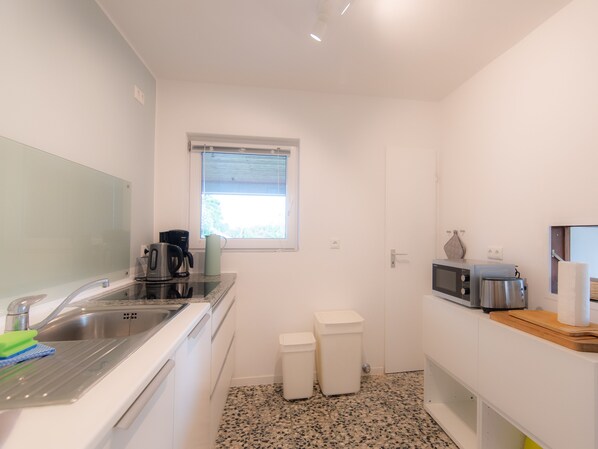 A compact kitchen with a sink, coffee maker, microwave, and a window.