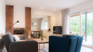 A modern living room with a fireplace, a television, and a dining area. - Spacious vacation apartment with garden, surrounded by greenery. (Westerdeichstrich)