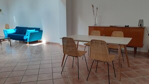A dining area with a table and chairs, a blue sofa, and a wooden cabinet.