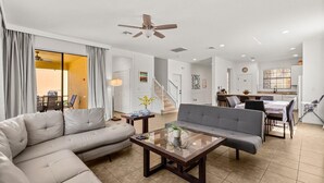 Ein geräumiges Wohnzimmer mit einer Couch, einem Couchtisch und einem Essbereich mit Stühlen und einem Tisch.