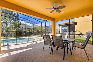 Un patio techado con piscina, mobiliario exterior y ventilador de techo.