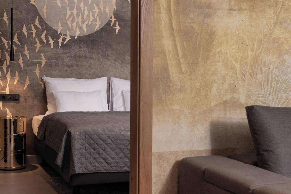 Une chambre moderne avec un grand lit, une table de chevet et une fresque murale.
