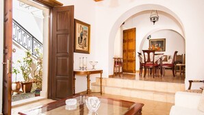 Amplia sala de estar con una mesa de centro de vidrio, una puerta de madera y un comedor con sillas y una mesa.