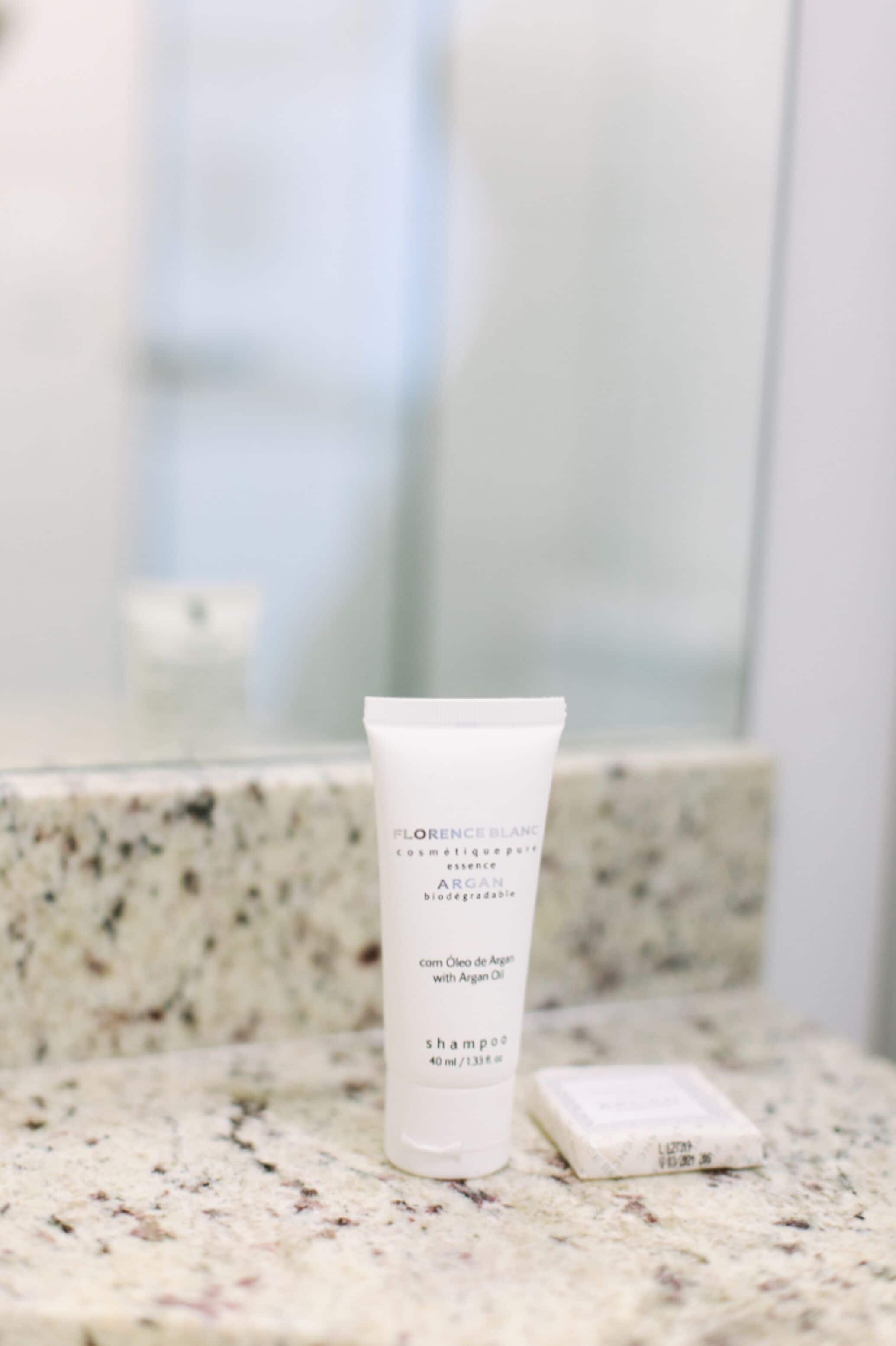 A bathroom with a marble countertop, a white tube of shampoo, and a bar of soap.