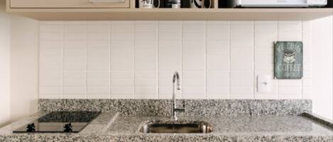 Una cocina con encimera de granito, pileta de acero inoxidable, armarios de madera y microondas integrado.