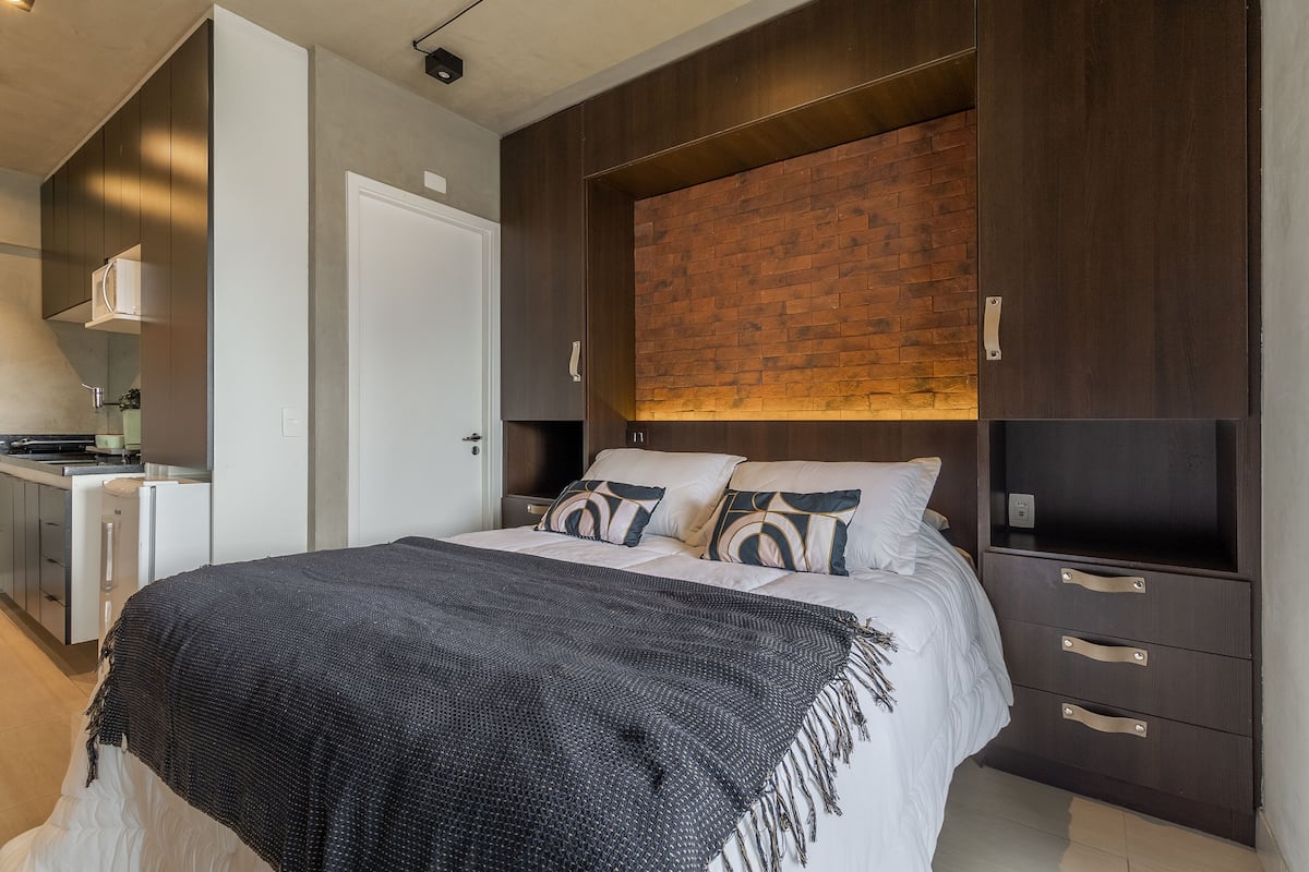 A modern bedroom with a large bed, a wooden headboard, and built-in drawers.