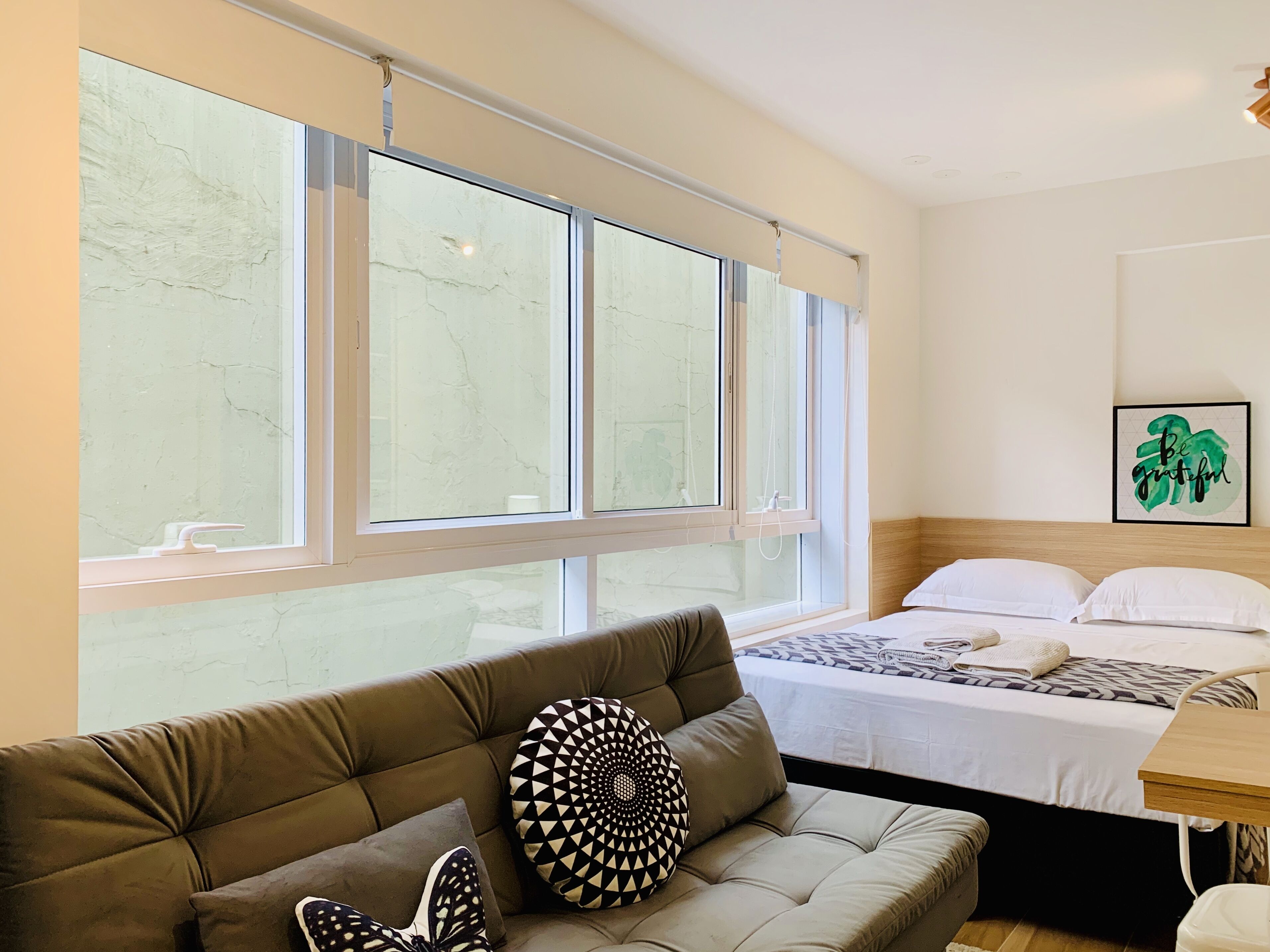 A modern hotel room with a large bed, a sofa, and a dining table.