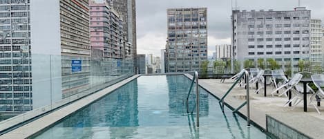 Una piscina al aire libre, sillones reclinables de piscina