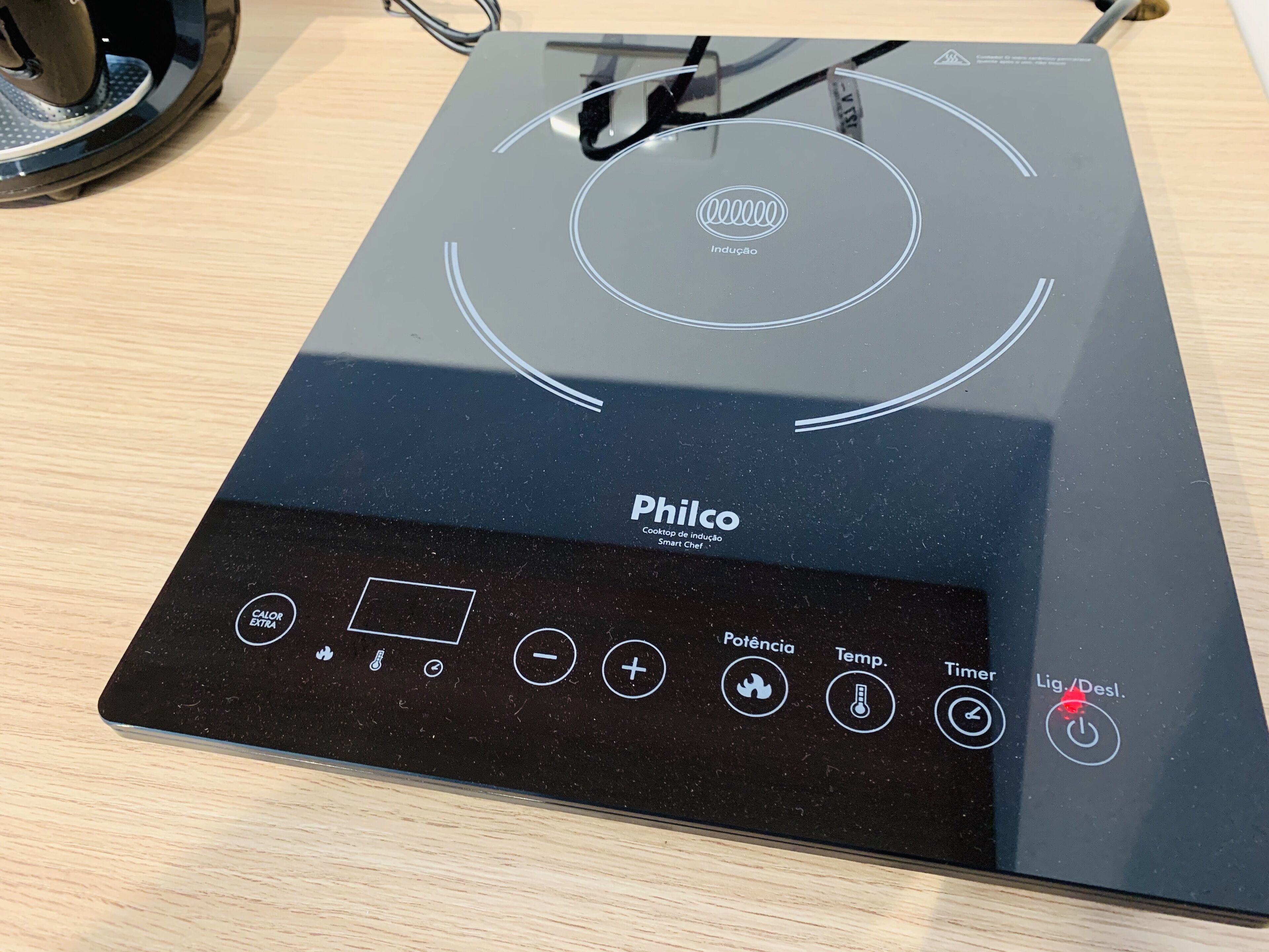 A black induction cooktop with a digital control panel labeled "Philco" and various buttons for settings.