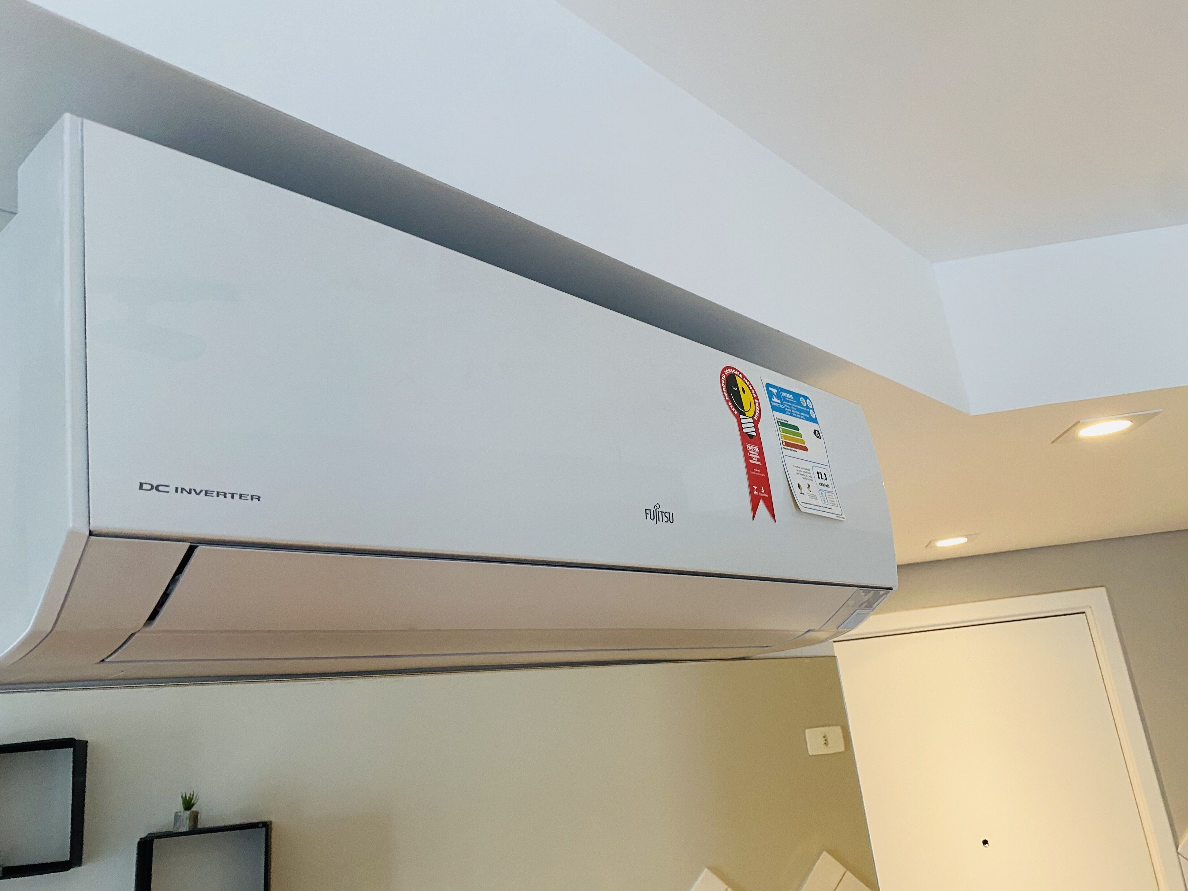 A white DC inverter air conditioner unit mounted on a wall with a Fujitsu logo and a red ribbon indicating an award.