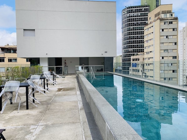 Una piscina al aire libre, sillones reclinables de piscina