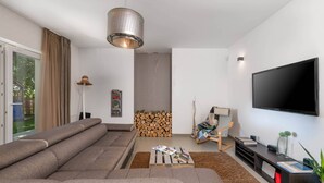 A modern living room with a large sofa, a coffee table, a TV, and a fireplace. - Villa Lounge Kapelana in Istria, Pool, Garden, BBQ (Svetvinčenat)