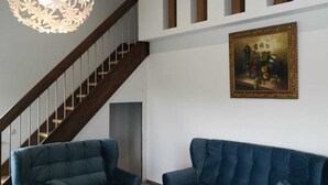 Un salon moderne avec un escalier, un plafond en bois et un tableau encadré accroché au mur.